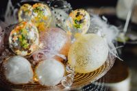 Kaboompics - Macro Spring Still Life of Floral Glass Easter Eggs and Glittered Ornaments in a Feather-Lined Nest