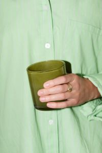 Kaboompics - Person in Light Green Shirt Holding an Olive Green Glass