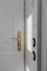 Antique Gold Door Handle and Black Light Switches on a White Paneled Door