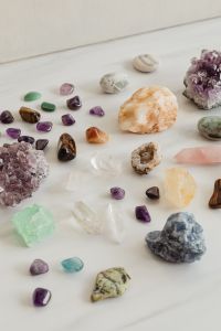 Kaboompics - Colorful Tumbled Gemstones and Raw Amethyst Cluster on a White Shelf