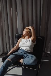 Kaboompics - Relaxed Woman Reclining in a Black Chair by Gray Curtains