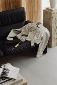 Kaboompics - Beige Jacket and Woven Handbag on a Black Leather Sofa