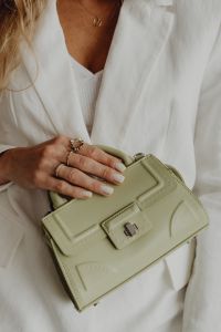 Kaboompics - Gold Rings and Hand Styled on Pale Green Leather Handbag