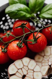 Kaboompics - Basil Leaves and Cherry Tomatoes Above Sliced Garlic, Vertical Crop