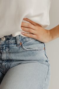 Kaboompics - Hand Resting at Waist beneath Loose White Blouse, Light Blue Jeans Fashion Detail