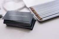 Kaboompics - Black Business Card Stack Beside a Colored Pencil Tin