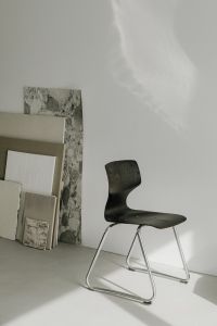 Kaboompics - Dark Sculptural Chair Beside Framed Art Panels