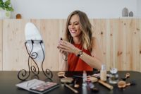 Kaboompics - Smiling Woman Checking Lipstick at a Vanity with Mirror and Cosmetics