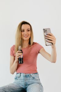 Kaboompics - Smiling Woman Taking a Smartphone Selfie Against a White Background, Everyday Lifestyle Content