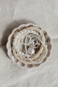 Kaboompics - Centered Pearl Necklace Arrangement in Scalloped Dish on Textured Beige Linen