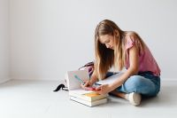 Kaboompics - Girl Solving Math Homework with Calculator and Phone