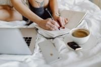 Kaboompics - Woman working on a laptop while enjoying a breakfast coffee and chocolate in bed