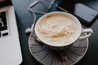 Kaboompics - Overhead Cappuccino and Earbuds beside Laptop and Phone on Dark Work Desk