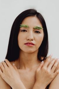 Kaboompics - Asian Woman Portrait with Crossed Arms and Greenery Eyebrow Makeup on White