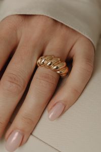 Kaboompics - Gold Ring on Woman's Hand Against Light Fabric