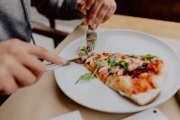 Kaboompics - Person Slicing Pizza for a Casual Restaurant Meal