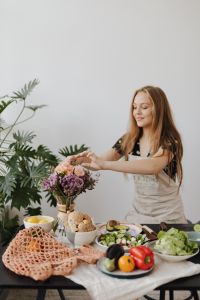 Kaboompics - Woman Arranging Flowers beside Fresh Salad Ingredients and Bread