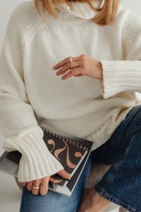 Kaboompics - Faceless Woman in White Sweater with Gold Rings Holding Book