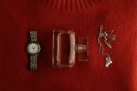 Kaboompics - Wristwatch Perfume Bottle and Jewelry on Burgundy Fabric