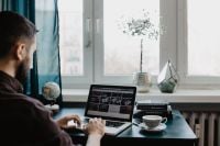Kaboompics - Man Working from Home beside Window with Laptop, Coffee, Books and Desk Decor