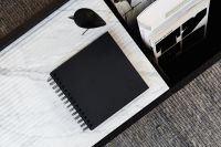 Kaboompics - Black Notebook and Wooden Bird Sculpture in a Minimalist Marble Workspace