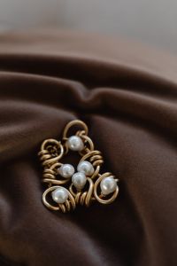 Kaboompics - Macro Close-Up of Gold Wire Pearl Jewelry on Brown Satin with Soft Copy Space