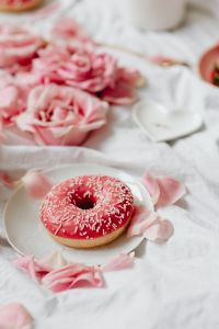 Kaboompics - Close-Up Pink Iced Donut with Roses on White Bedding
