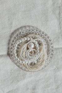 Kaboompics - Overhead Pearl Necklace Arrangement in a Faceted Glass Bowl on Textured Linen