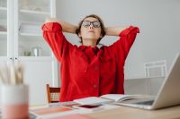 Kaboompics - Home Office Stretch Break: Woman Leaning Back with Arms behind Her Head beside Laptop