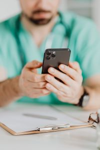 Kaboompics - Doctor Browsing Phone During Office Work