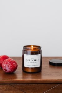 Kaboompics - Amber Jar Candle with Plums and Lid on Wood for Product Packaging Photos