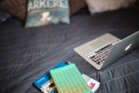 Kaboompics - Laptop with books on a bed