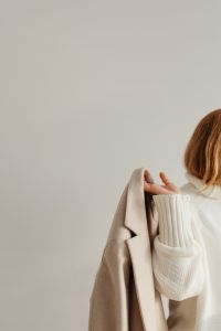 Kaboompics - Faceless Woman in White Sweater Putting on Beige Coat