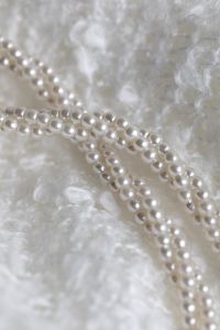 Kaboompics - Curved Pearl Necklace Strands on Textured White Fabric, Minimalist Jewelry Background