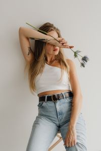 Kaboompics - Woman Posing with Purple Flower Stem across Her Face, White Crop Top and Denim Jeans