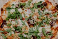 Kaboompics - Restaurant-Style Pizza with Greens on a Wooden Board