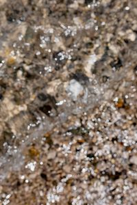 Kaboompics - Abstract Wet Pebbles with Reflective Shoreline Bokeh