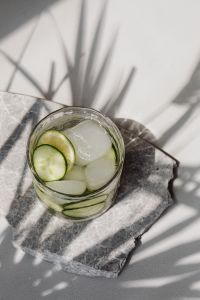 Kaboompics - Top-Down Cucumber and Lime Detox Water with Ice on Dark Marble, Geometric Window Shadows and White Copy Space