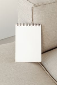 Kaboompics - Portrait Sketchbook Mockup Against a Linen Sofa Cushion
