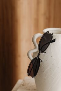 Kaboompics - Black Sunglasses Hanging from a White Vase