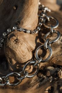 Kaboompics - Close-Up Silver Link Necklace with Crystal Detail on Weathered Wood