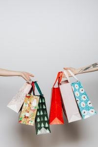 Kaboompics - Hands Exchanging Colorful Christmas Gift Bags Against a Clean White Studio Background