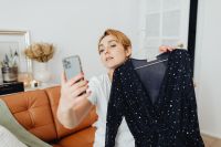Kaboompics - Online Boutique Owner Presenting a Navy Dress for Smartphone Shopping Content