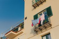 Kaboompics - Yellow Seaside Home with Green Shutters and Laundry Drying on the Balcony