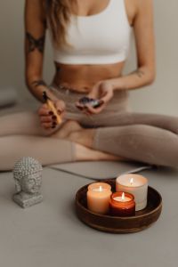 Kaboompics - Seated Woman Holding Smoldering Sage and Crystal Near Candles