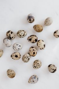 Kaboompics - Scattered Quail Eggs on White Marble with Open Space, Vertical Easter Flat Lay