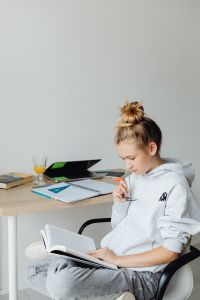 Kaboompics - Teenager Reading Textbook with Notebook and Laptop