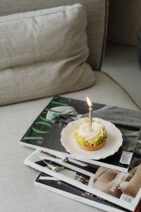Kaboompics - Small Cake with a Lit Candle on Magazines