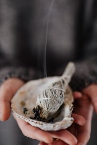 Kaboompics - Smoke Rising from a Sage Bundle in a Shell against a Dark, Moody Background