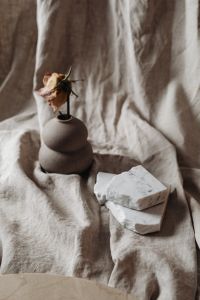 Kaboompics - Dried Rose, Ceramic Vase and Marble Pieces on Textured Linen
